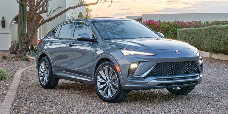 A dark gray 2024 Buick Envista GX parked on a gravel driveway in front of a white building with succulents