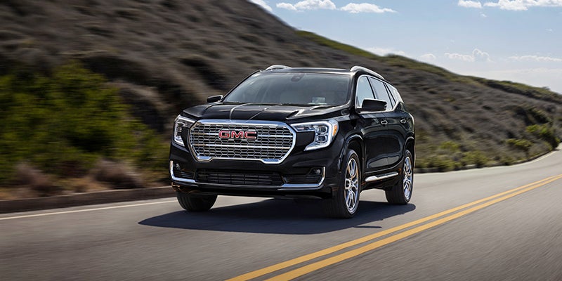 Front view of a black GMC Terrain compact SUV driving on an asphalt road