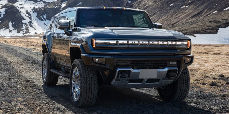 A dark grey electric Hummer SUV on a gravel road
