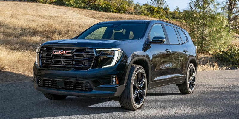 Front 3/4 shot of a dark gray GMC Terrain SUV driving right to left on an asphalt road