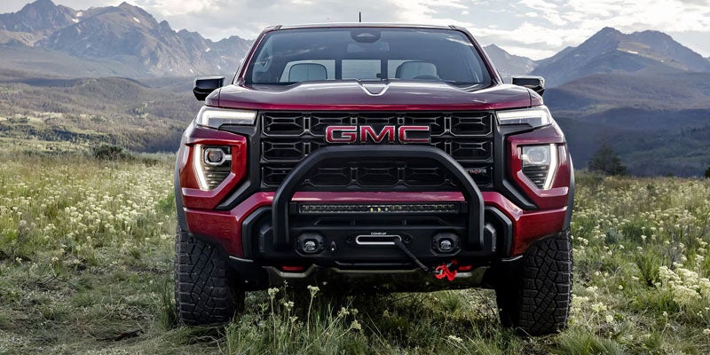 Front view of a red GMC pickup truck with a heavy-duty bumper, winch, and light bar